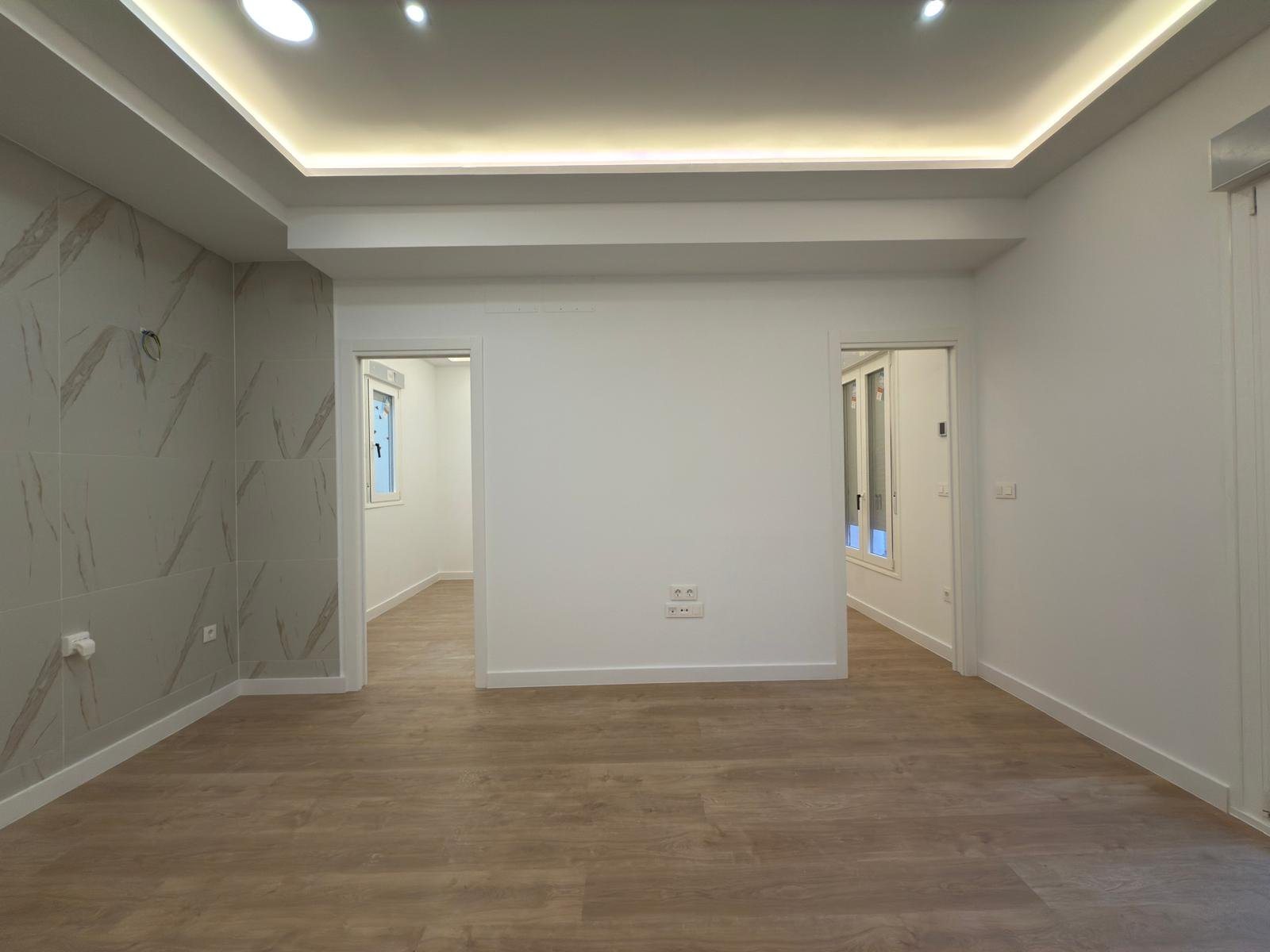 Salón reformado con luz indirecta y frente de mármol